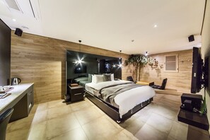 Un dormitorio moderno con una cama grande, mesitas de noche, un escritorio y un televisor.
