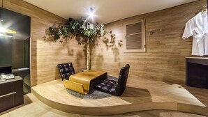 Una habitación moderna con un área de descanso curvada, una pared de madera, una planta en maceta y una bata blanca colgada en la pared.
