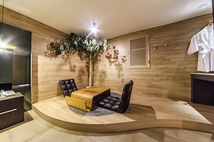Una habitación moderna con un área de descanso curvada, una pared de madera, una planta en maceta y una bata blanca colgada en la pared.