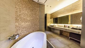 Un baño moderno con una bañera independiente, un espejo grande y un tocador con lavabo y encimera.
