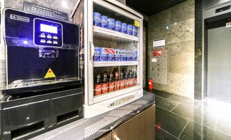 Máquina expendedora con bebidas y un refrigerador pequeño lleno de refrescos.
