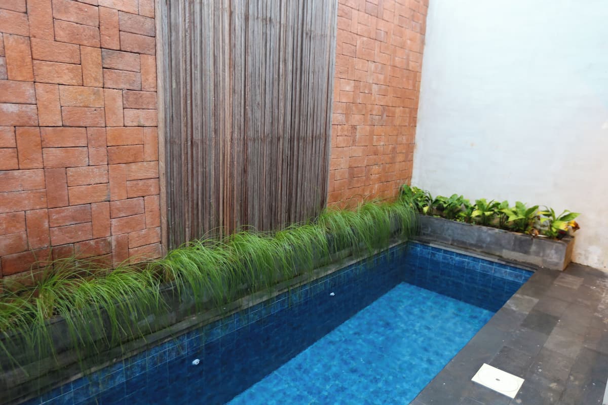 A swimming pool with a brick wall and a wooden panel on one side.