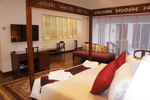 Un dormitorio de estilo tradicional con cama con dosel, un escritorio y un televisor.