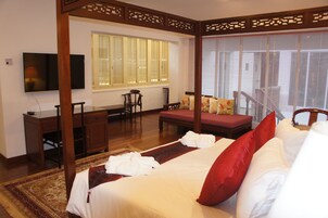 Un dormitorio de estilo tradicional con cama con dosel, un escritorio y un televisor.