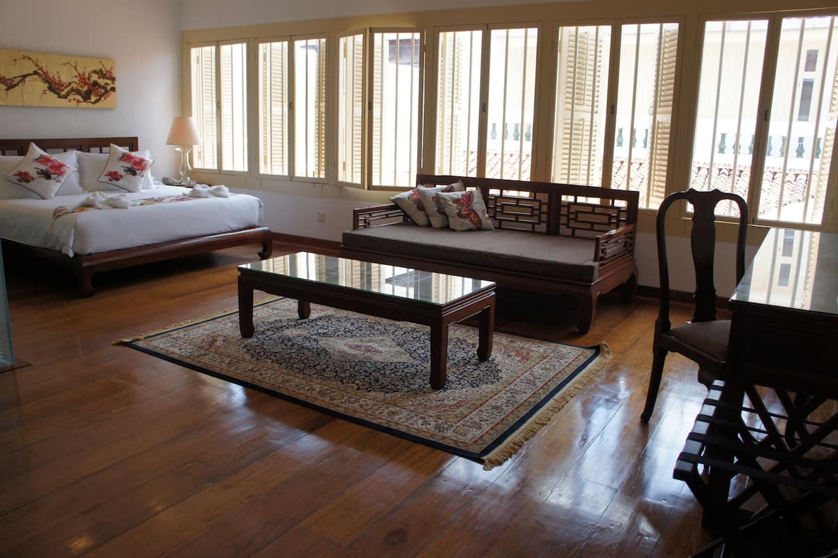 A spacious room with a bed, a sofa, a dining table, and a chair.
