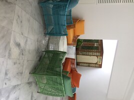 Una habitación con suelo de baldosas, una cama con cabecera blanca y una ventana con vista a un muro de ladrillo.