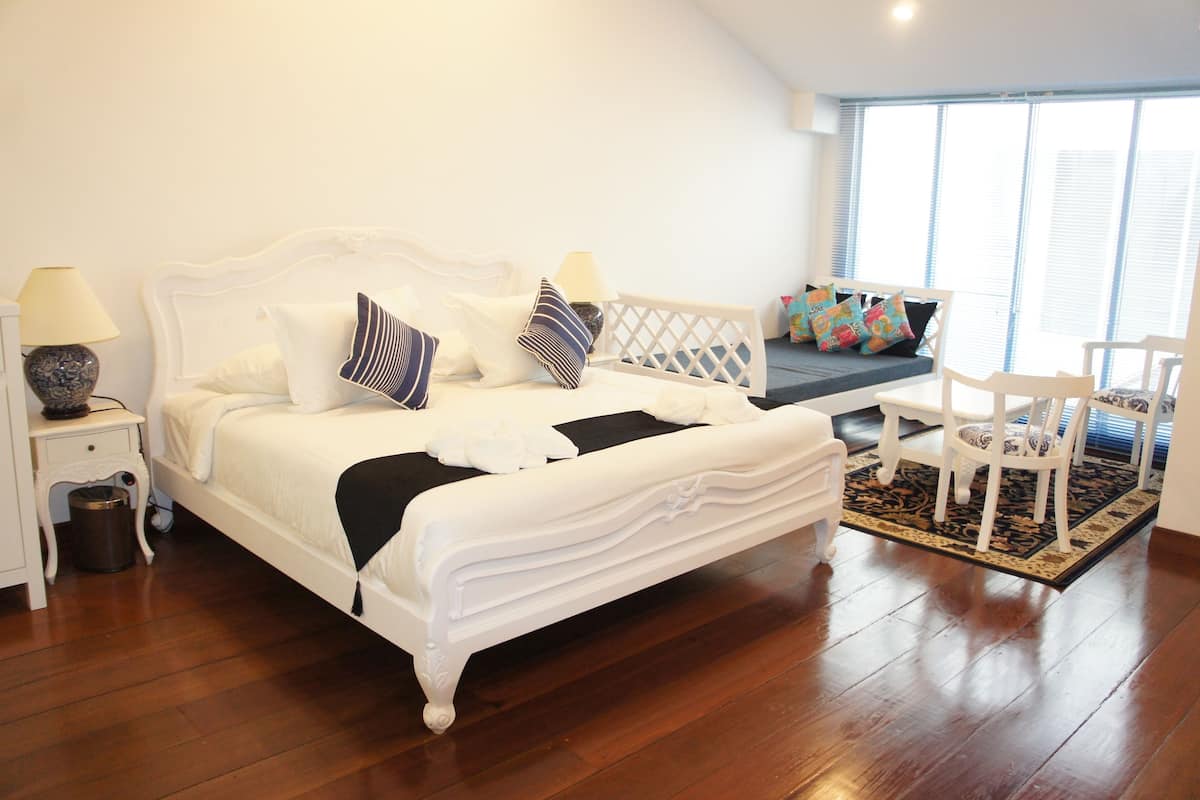 A bedroom with a large bed, bedside tables, a bench, and a chair.