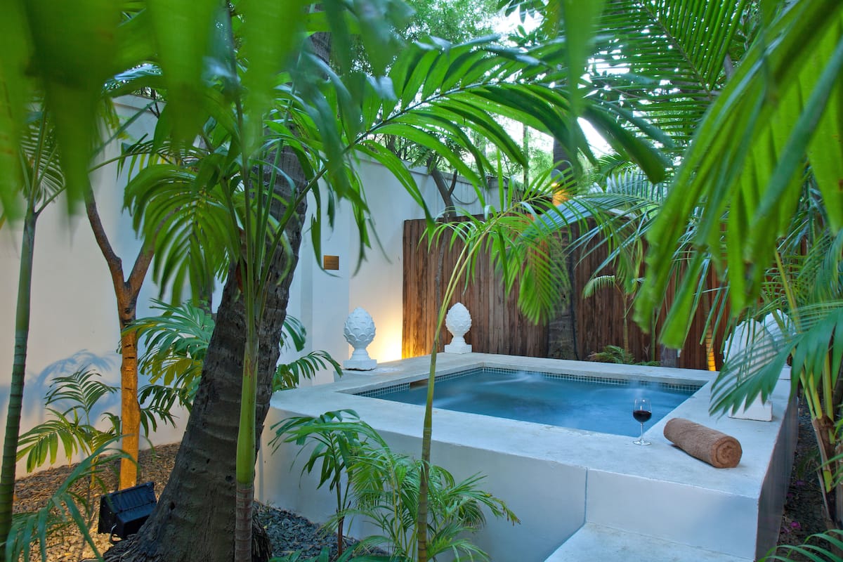 A hot tub surrounded by lush greenery and a wooden fence.