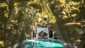 A swimming pool surrounded by palm trees and a gazebo.
