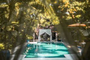 A swimming pool surrounded by palm trees and a gazebo.