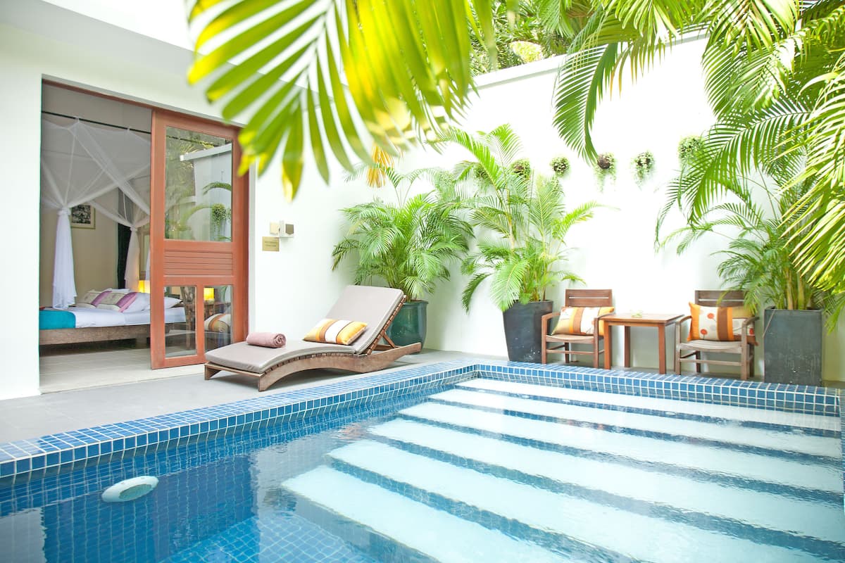 A swimming pool with lounge chairs and potted plants.
