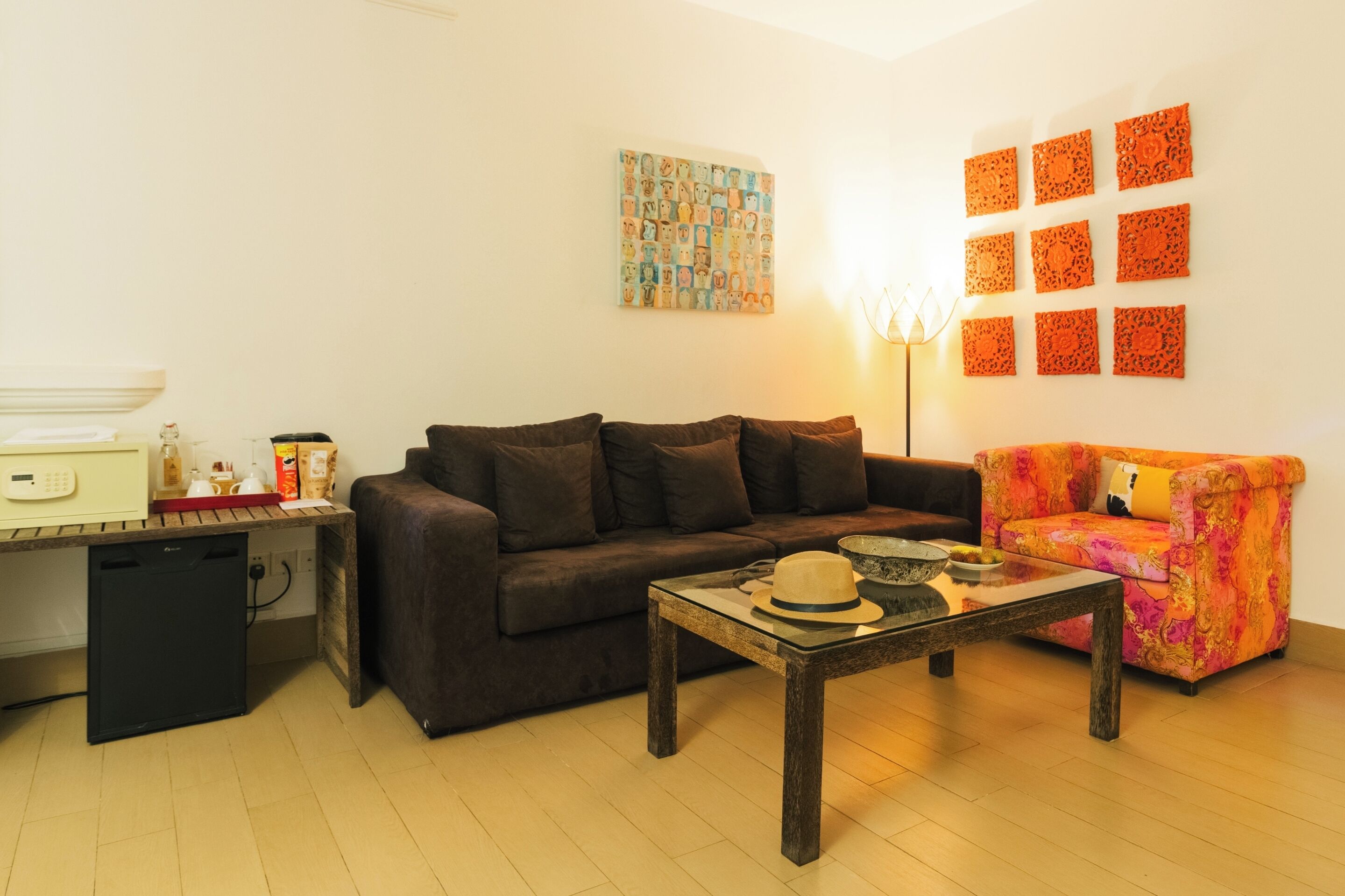 A living room with a brown sofa, a colorful armchair, a coffee table, and a painting on the wall.