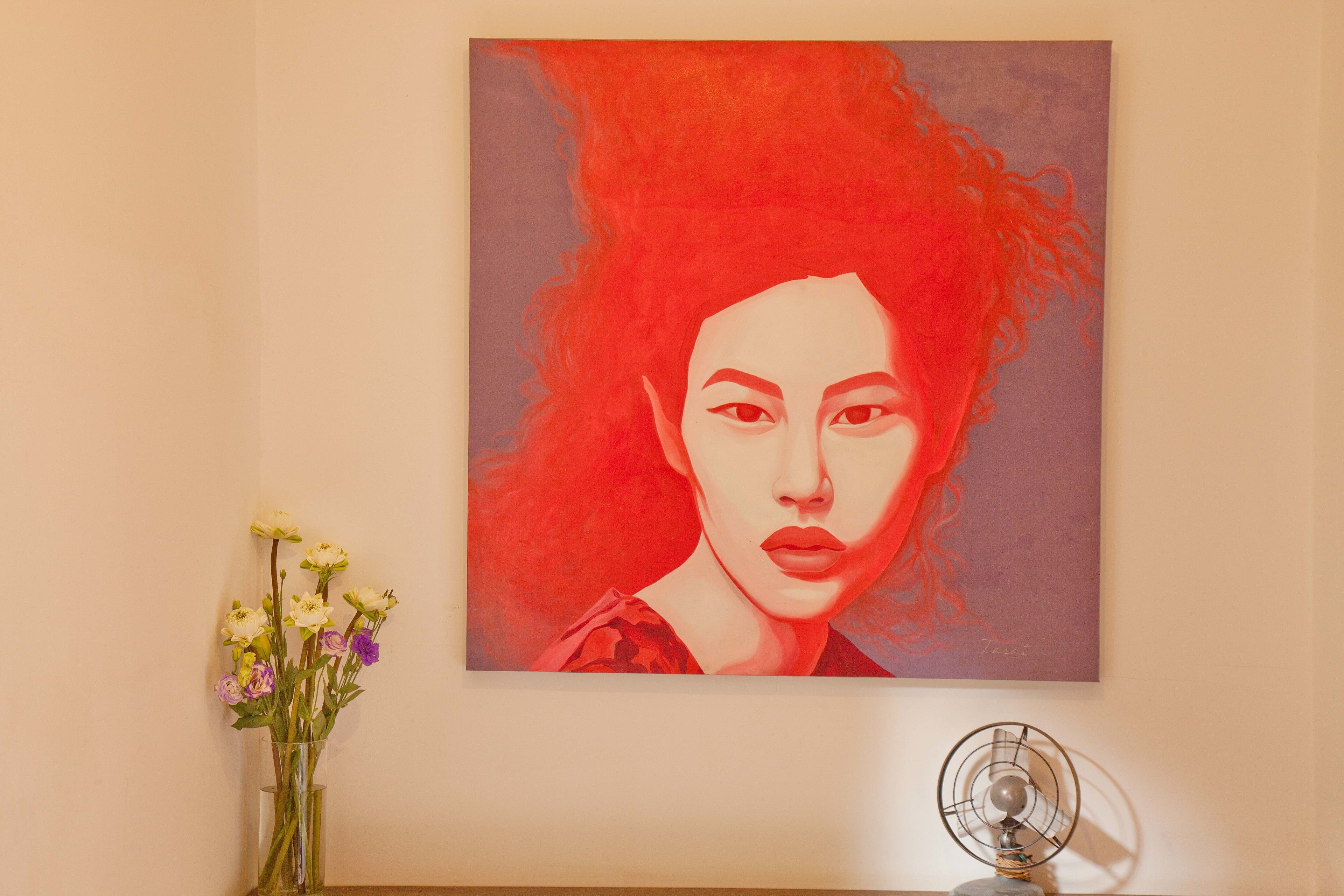A painting of a woman with red hair on a wall.
