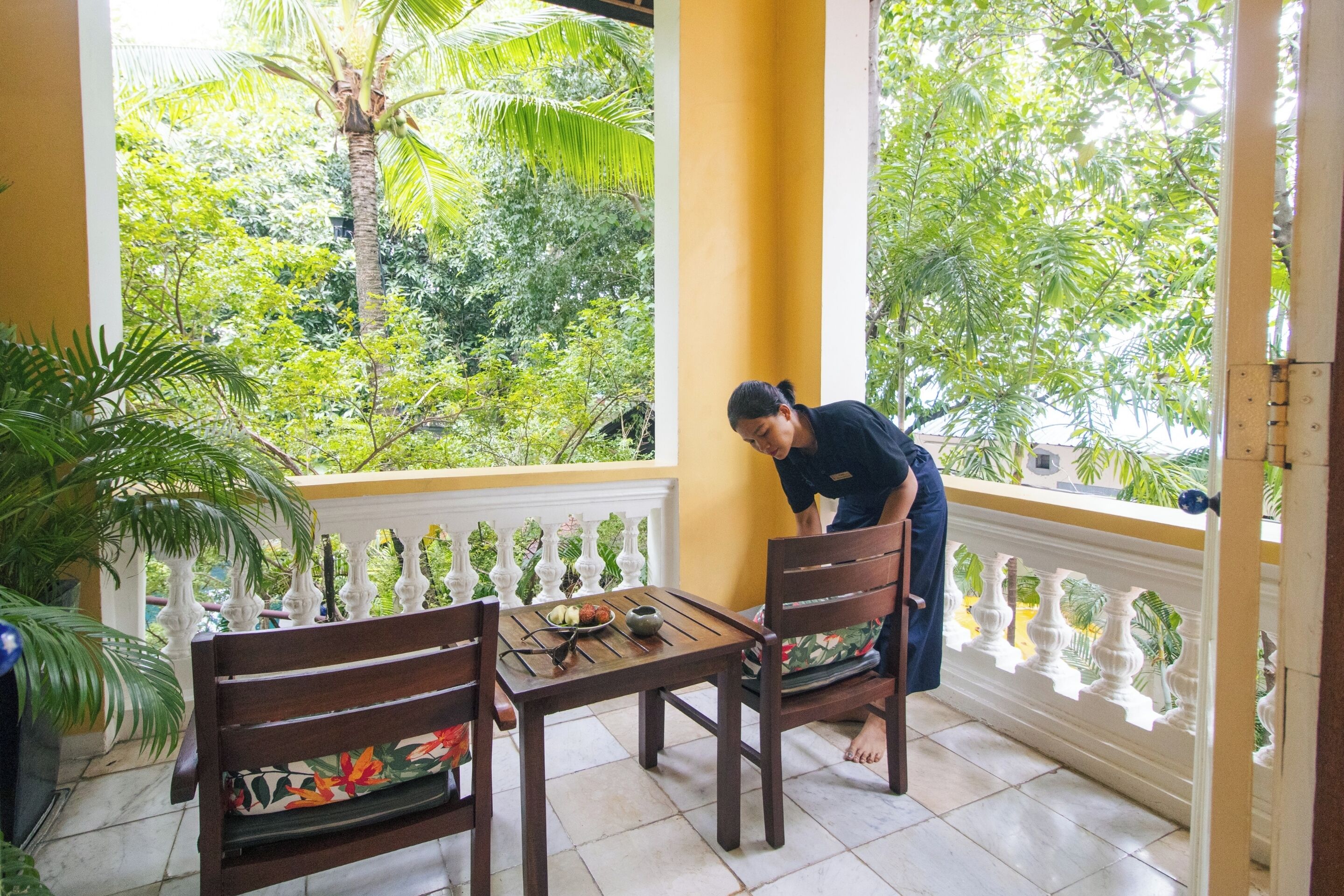 A balcony with a table and chairs, overlooking a lush garden.