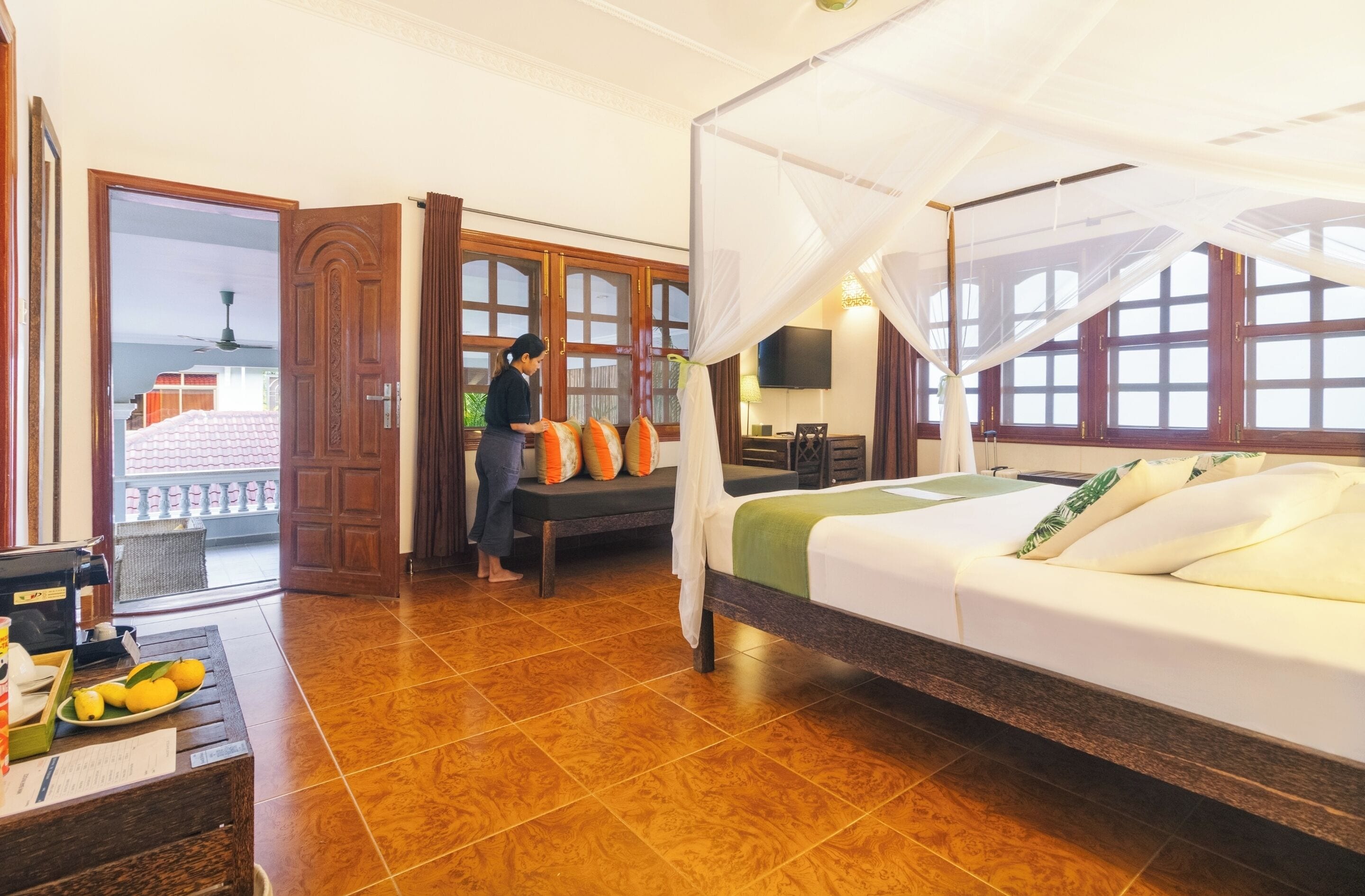 A hotel room with a bed, a desk with a computer, a TV, and a balcony with a view.