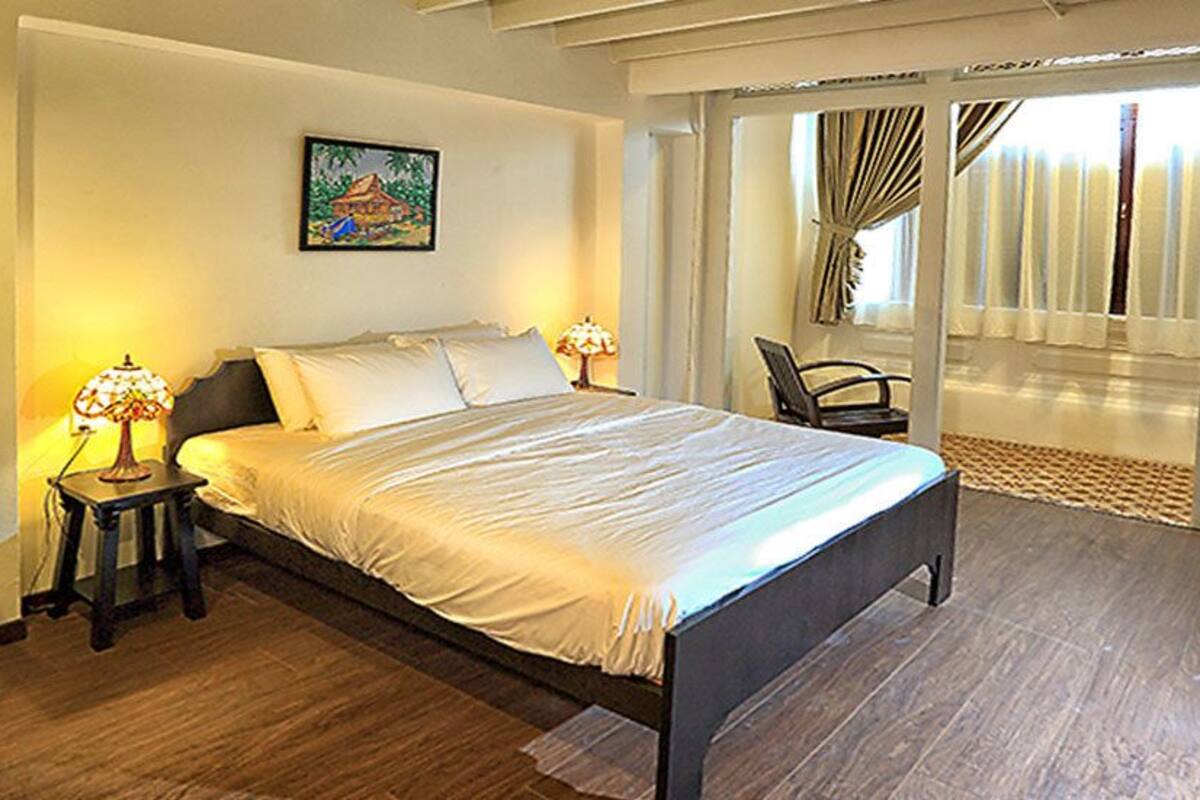 Une chambre d’hôtel avec un lit, un bureau, une chaise et une fenêtre avec des rideaux.