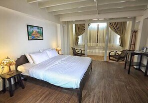 A hotel room with a bed, a desk, a chair, and a window with curtains. - Heeren By The River (Malacca City)