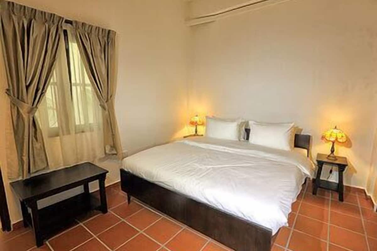 Une chambre à coucher avec un lit, deux tables de chevet, une commode et une fenêtre avec des rideaux.