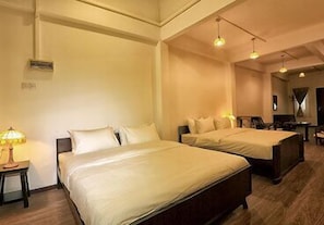 Habitación de hotel con dos camas, una mesita de noche, una lámpara y un escritorio con silla.