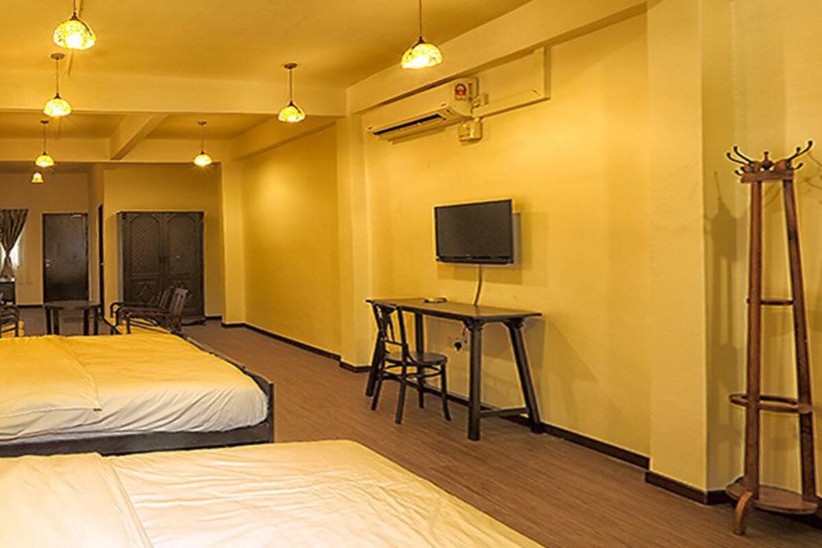 Une chambre d’hôtel avec deux lits, un bureau, une chaise, une télévision et un porte-manteau.
