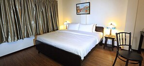 Ein Hotelzimmer mit einem großen Bett, zwei Nachttischen mit Lampen, einem Sessel und einem Gemälde an der Wand.