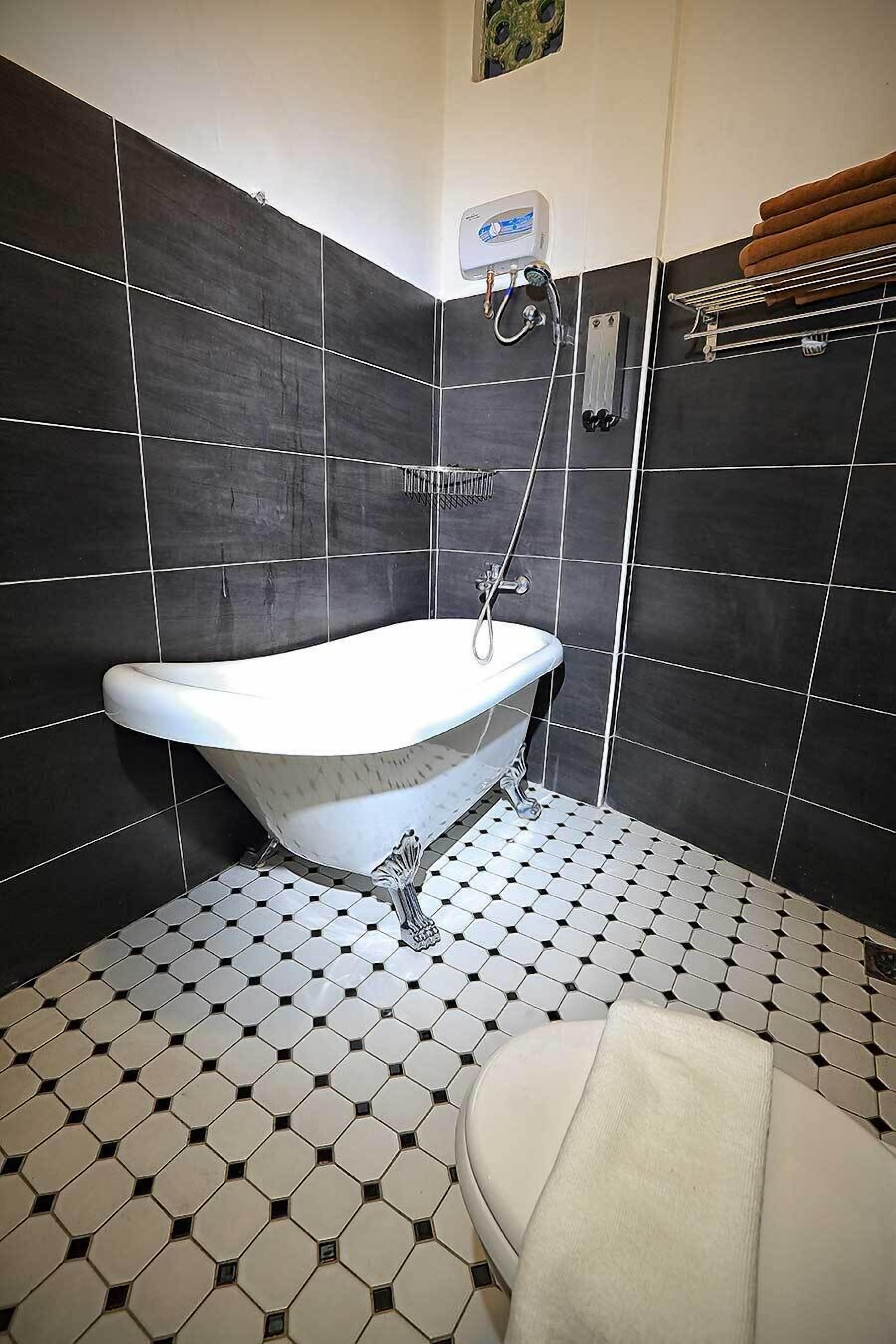 A bathroom with a freestanding bathtub, a toilet, and a towel rack.