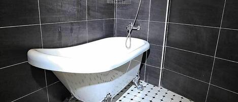 A bathroom with a freestanding bathtub, a toilet, and a towel rack.