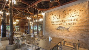 Een restaurantinterieur met open bakstenen muren, houten balken en gedekte tafels.