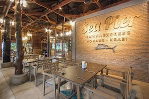 A restaurant interior with exposed brick walls, wooden beams, and tables set for dining.
