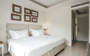 A bedroom with a bed, a nightstand, a wall-mounted lamp, and framed fish pictures.