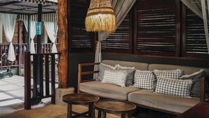 Een gezellig zitgedeelte met een bank, twee ronde tafels en een hanglamp.