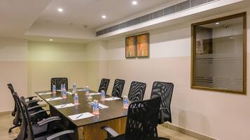 A conference room with a long table, black chairs, water bottles, and a glass partition.