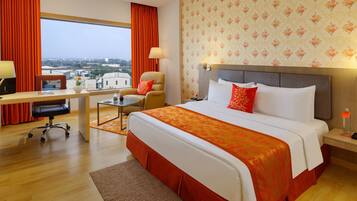 Habitación de hotel con cama, escritorio, silla y vistas de la ciudad.