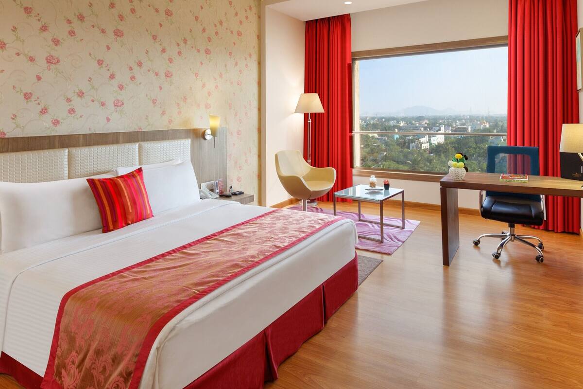 Una habitación de hotel con una cama grande, un escritorio, una silla y un televisor.