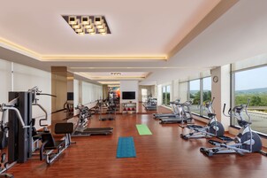 Un gimnasio amplio con diverso equipamiento de ejercicio, ventanas grandes y un diseño moderno.