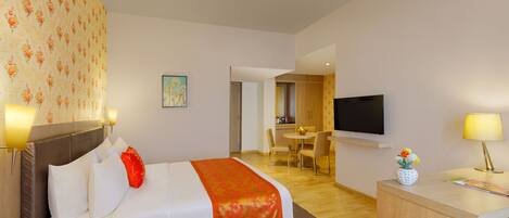 A hotel room with a bed, a desk, a TV, and a dining area.