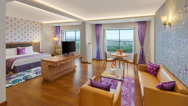 Une chambre d’hôtel moderne équipée d’un lit, d’une télévision, d’un bureau, d’un canapé et d’un coin repas avec vue.