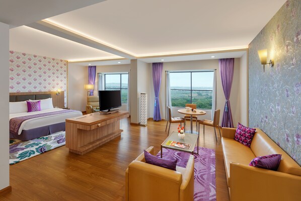 Une chambre d’hôtel moderne équipée d’un lit, d’une télévision, d’un bureau, d’un canapé et d’un coin repas avec vue.