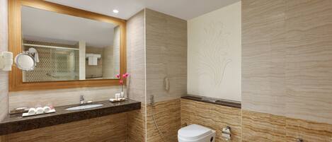 A modern bathroom with a marble vanity, a separate toilet, and a bathtub.