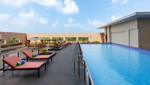 A rooftop pool area with lounge chairs and a gazebo.