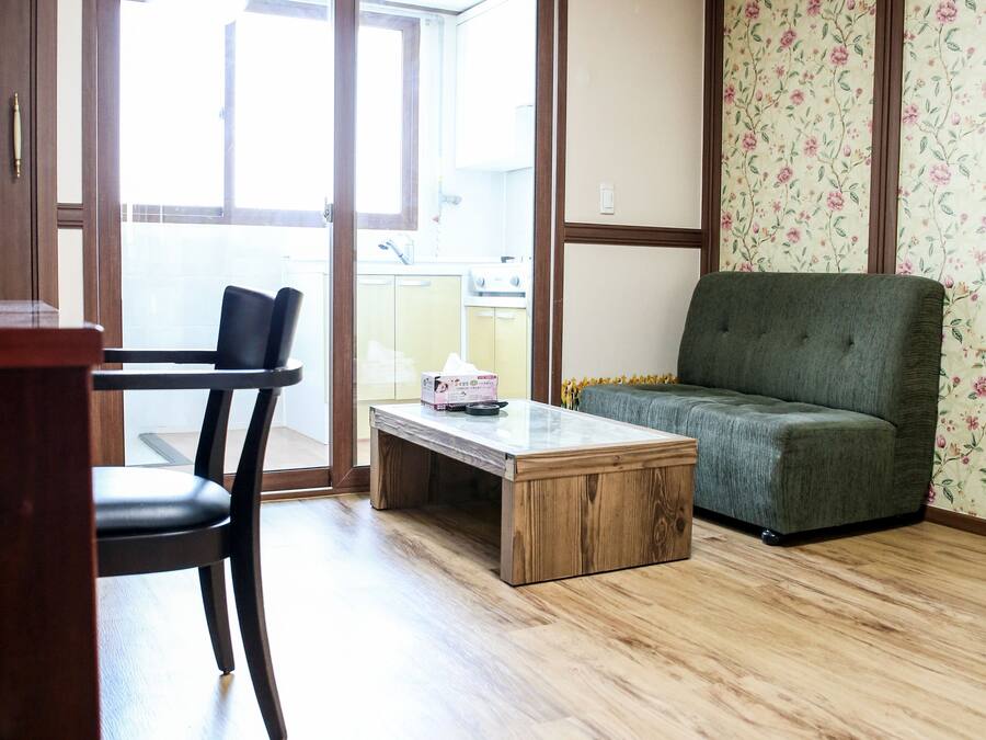 A living room with a wooden floor, a green sofa, a wooden coffee table, and a black chair.
