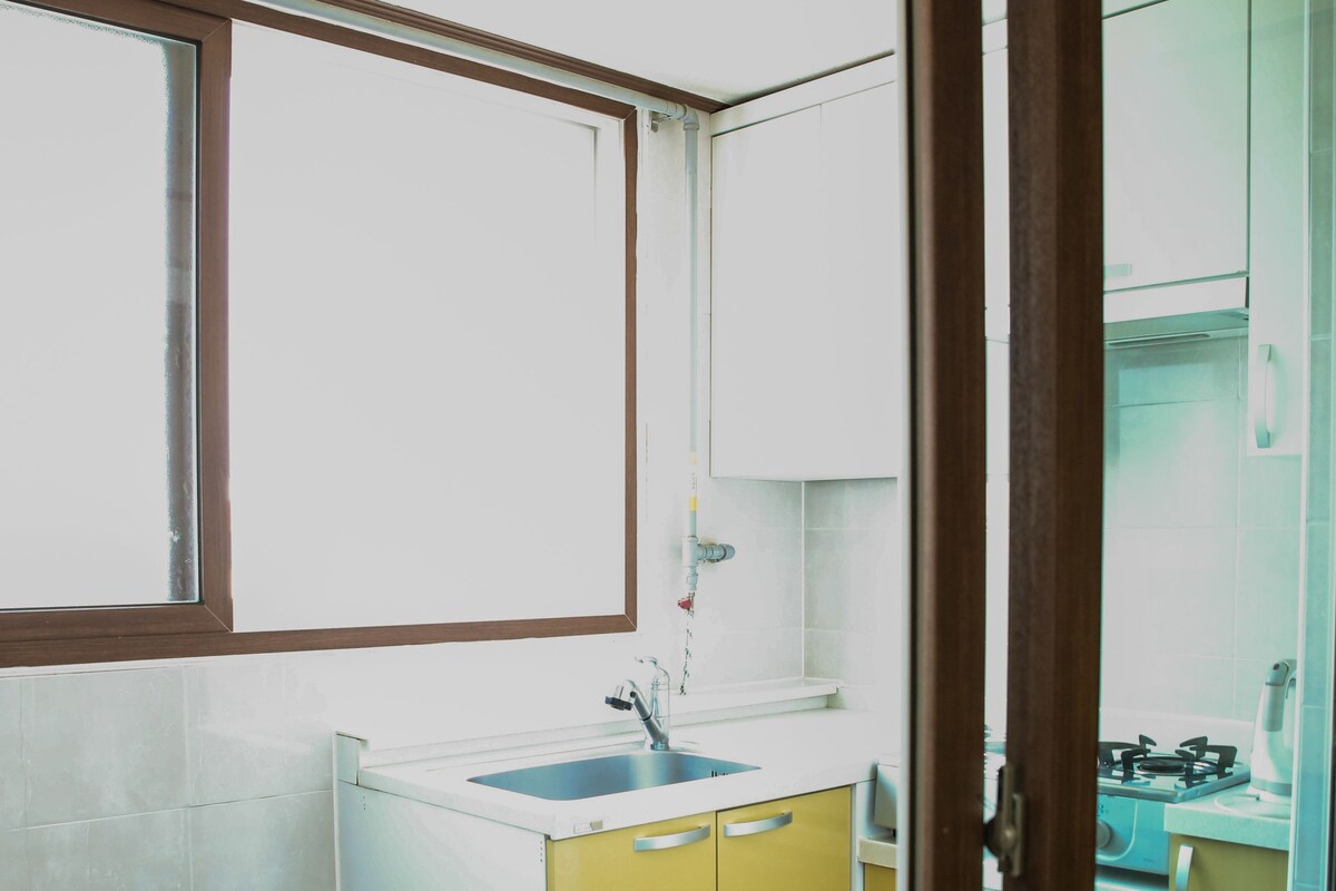 A compact kitchen with a window, a sink, and a stove.