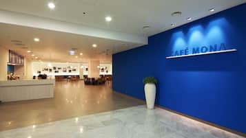A modern lobby with a reception desk, seating area, and a large potted plant.