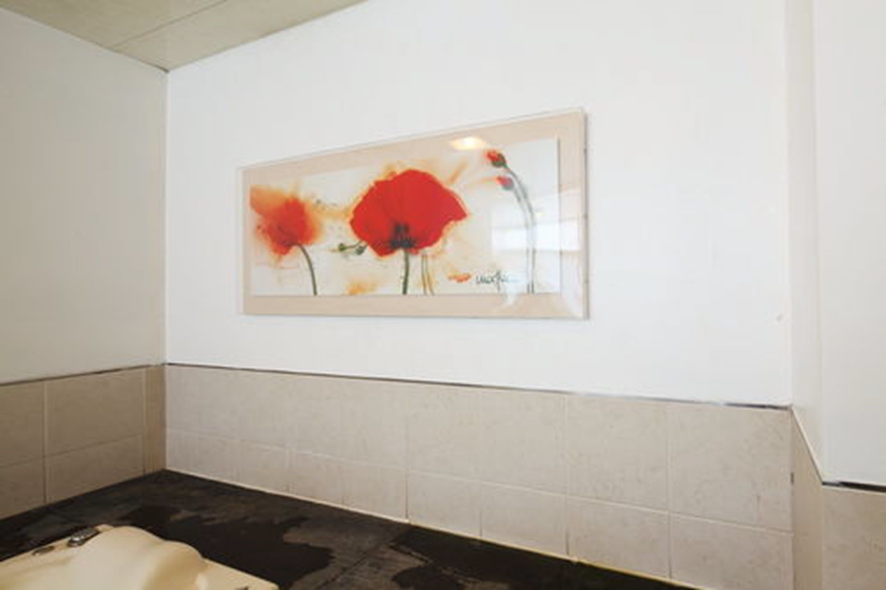 A bathroom with a framed artwork of red flowers on the wall.
