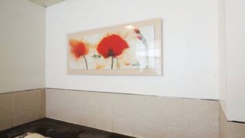 A bathroom with a framed artwork of red flowers on the wall.