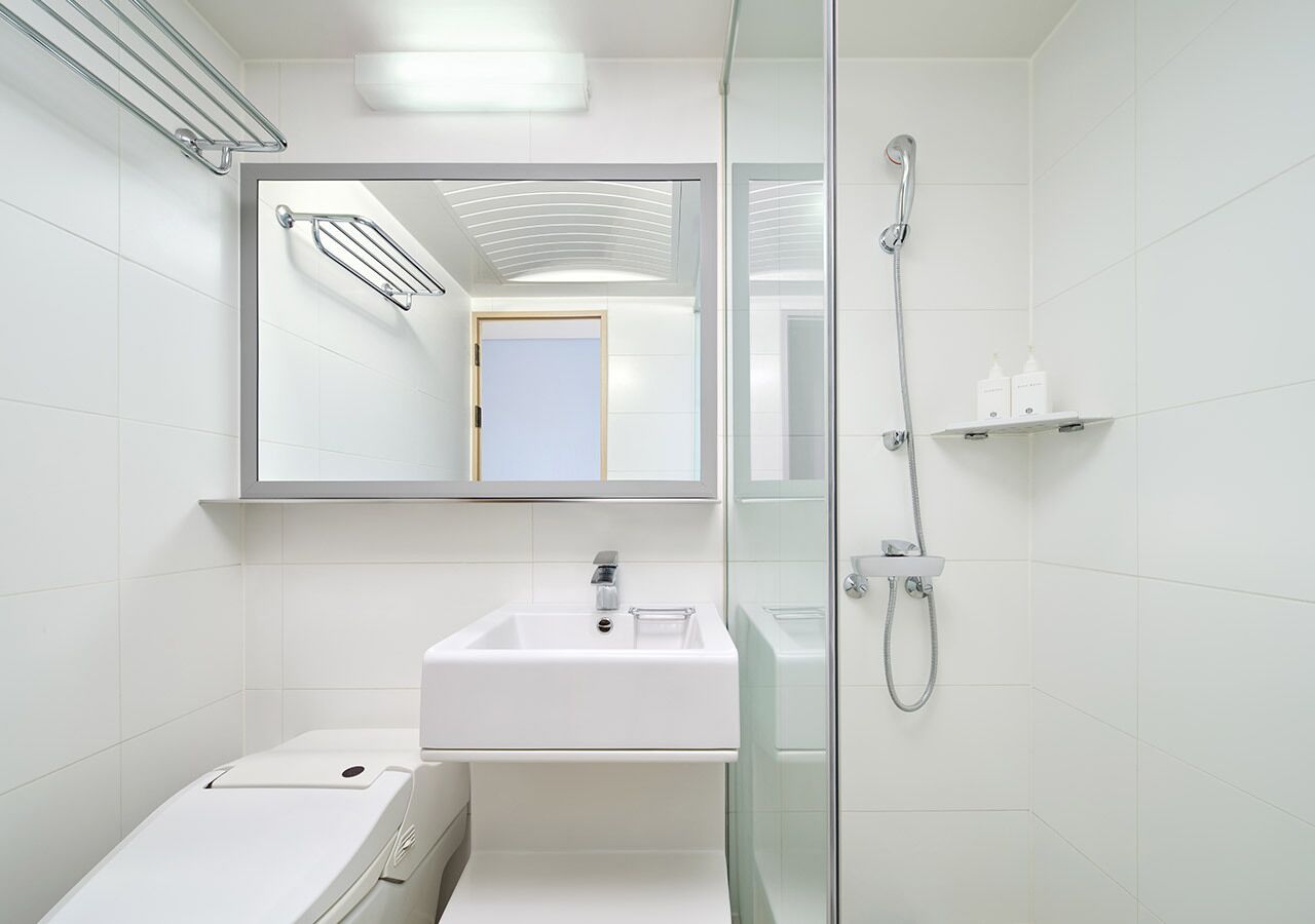 Un bagno moderno con cabina doccia in vetro, un lavandino bianco e uno specchio sopra.