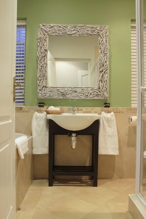 A bathroom with a sink, mirror, and two towels hanging on the wall.