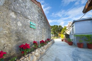A narrow alley with a stone wall, potted plants, and a clear blue sky. - Baisha31 (Hengchun)