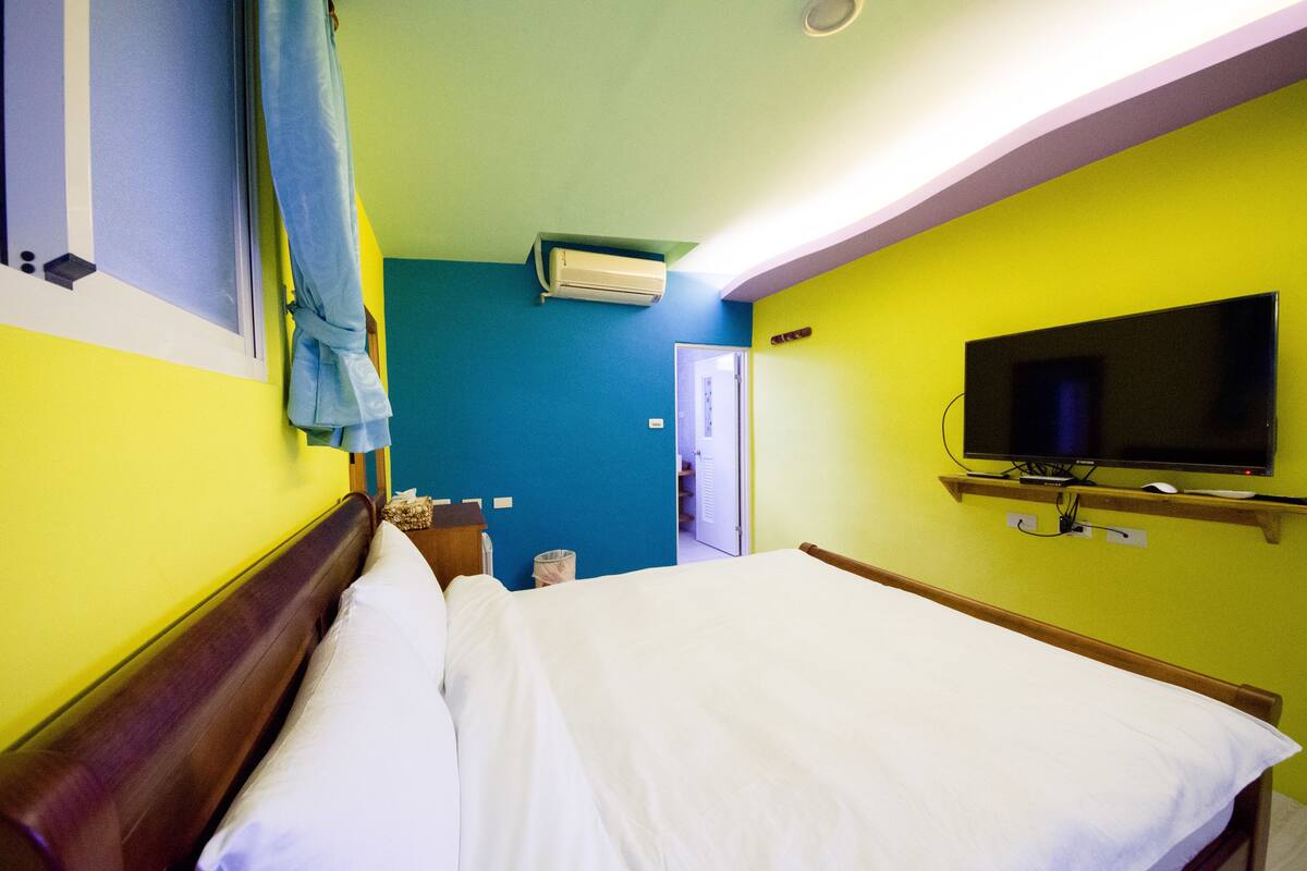 Una habitación de hotel con una cama, televisión y aire acondicionado.