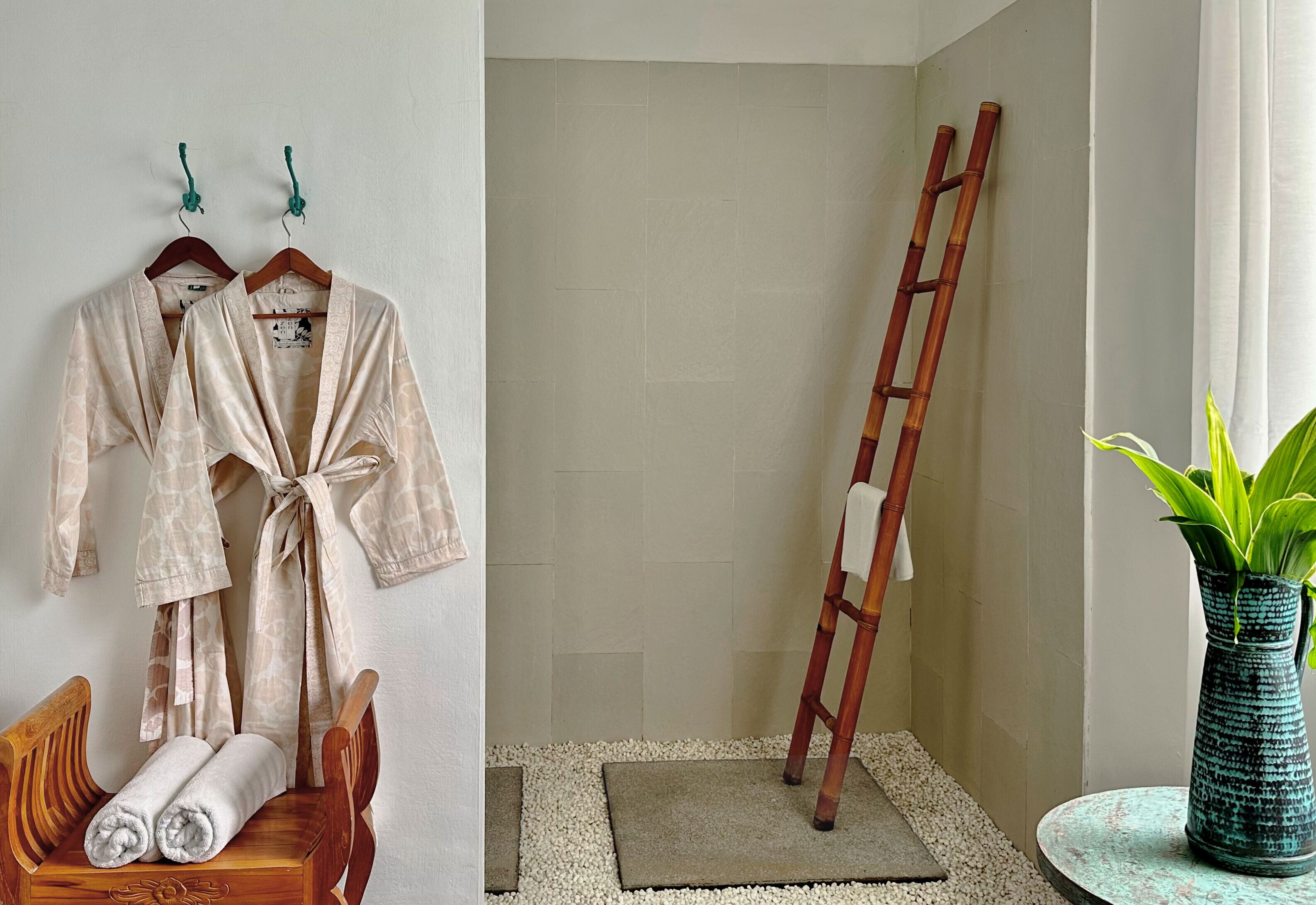 Un baño con un banco de madera, un perchero con batas, una escalera y una planta en maceta.
